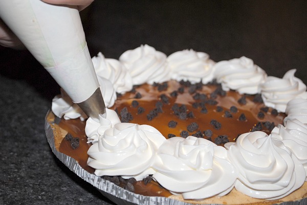 piping whipe cream on pumpkin pie